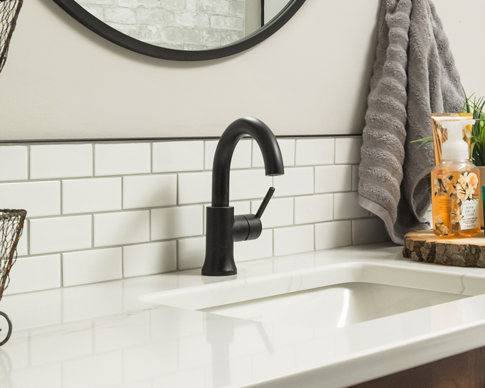 Delta® matte black vanity faucet with single lever, installed on a white, cultured marble bathroom vanity. Photo by Illia Sternichuk.