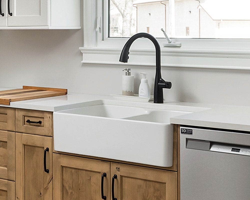 Franke® farmhouse kitchen sink. White sink with black faucet. Photo by Illia Sternichuk.