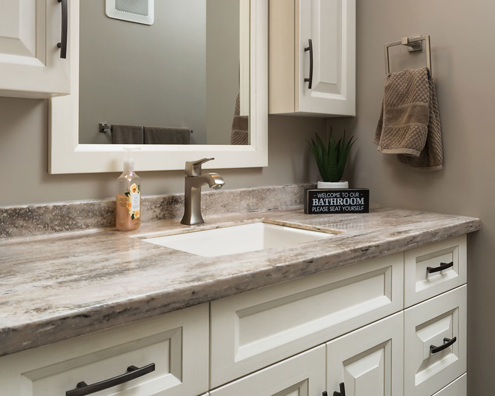 Solid surface vanity countertop with a black/gray/beige natural pattern, installed on a white recessed panel vanity with matte black cabinet pulls. Photo by Illia Sternichuk.